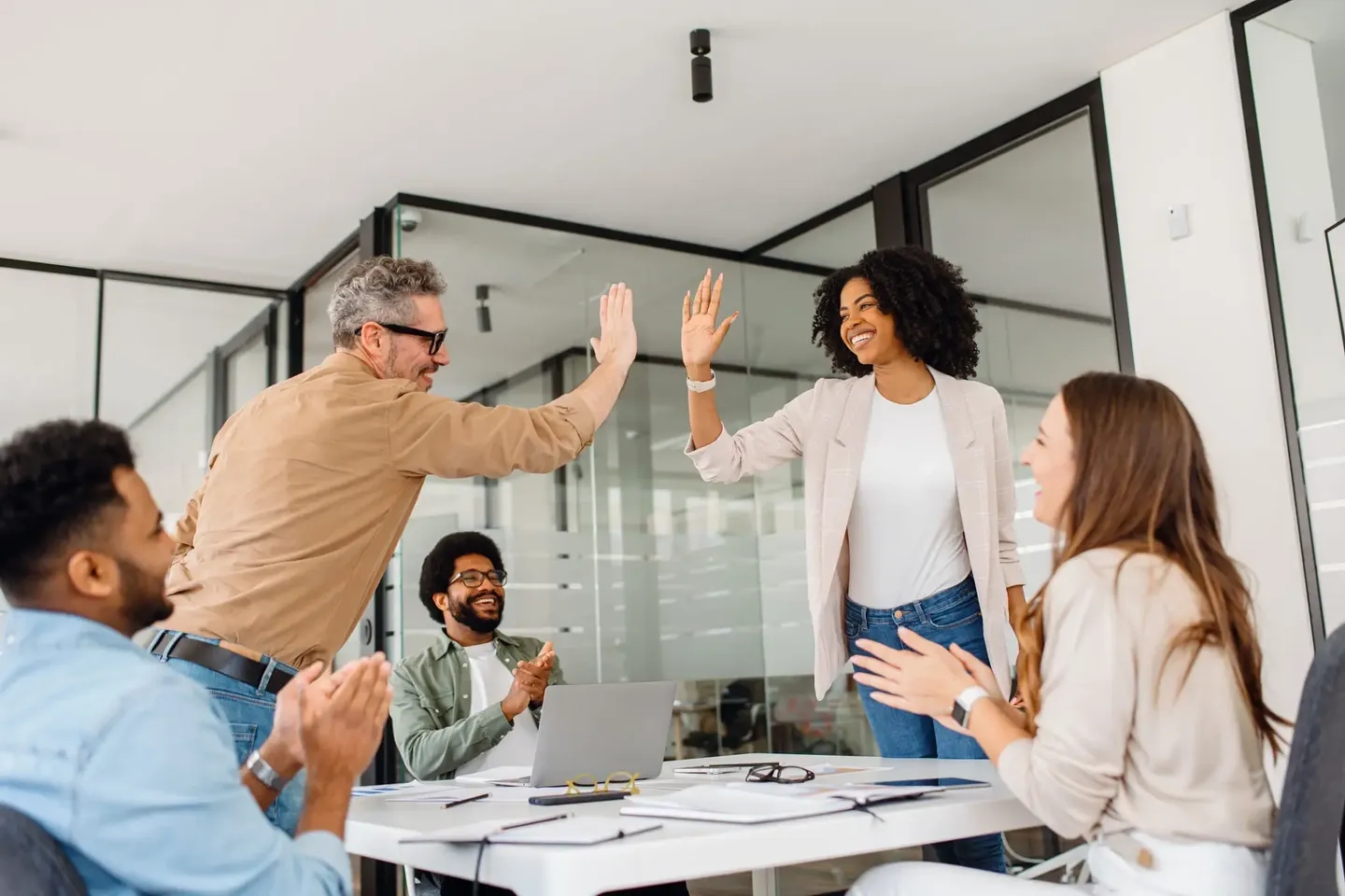 Colleagues celebrating success with a high-five in a modern office.
